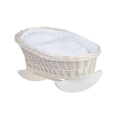 softly lit wicker doll cradle with white bedding in a cozy nursery corner