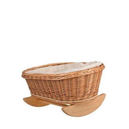 a child's hands gently rocking a wicker doll cradle with soft white bedding