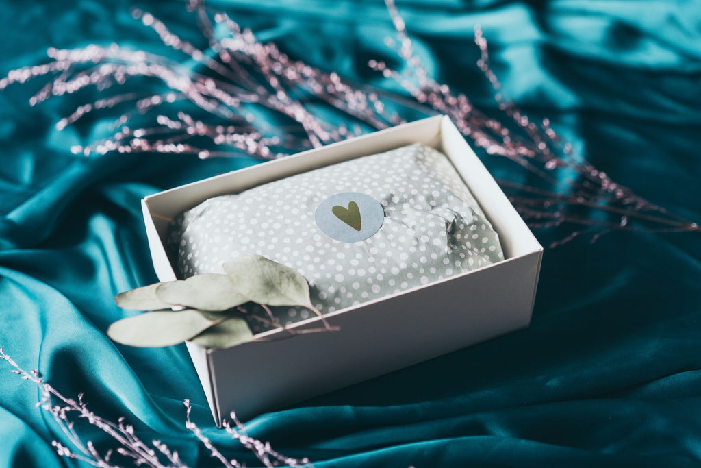 elegant with love gift box open on a marble surface revealing avocado lip balm and orange body cream