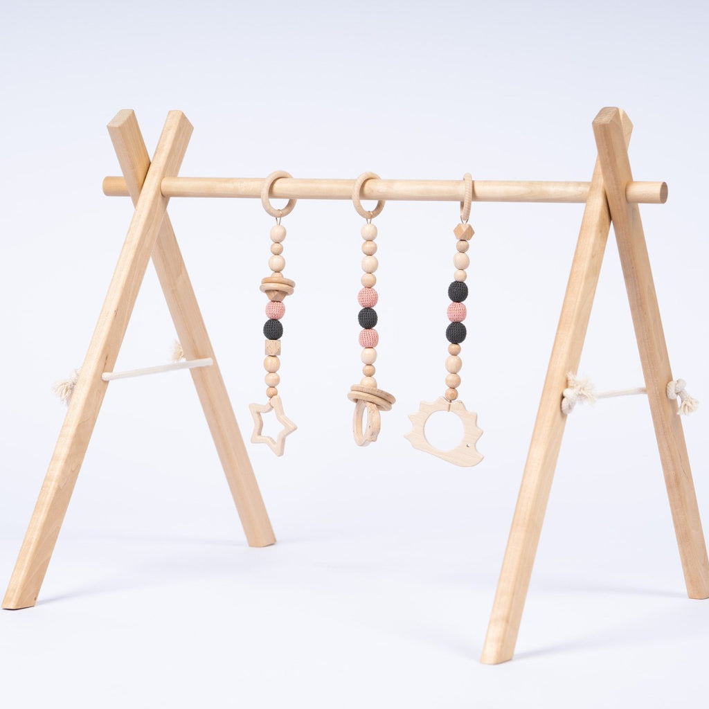 a baby reaching for a dangling wooden toy on the gym during playful tummy time