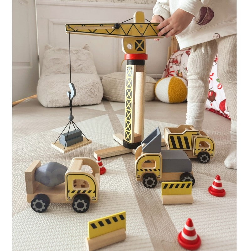 a child's hands playing with the woopie green wooden crane lifting a block