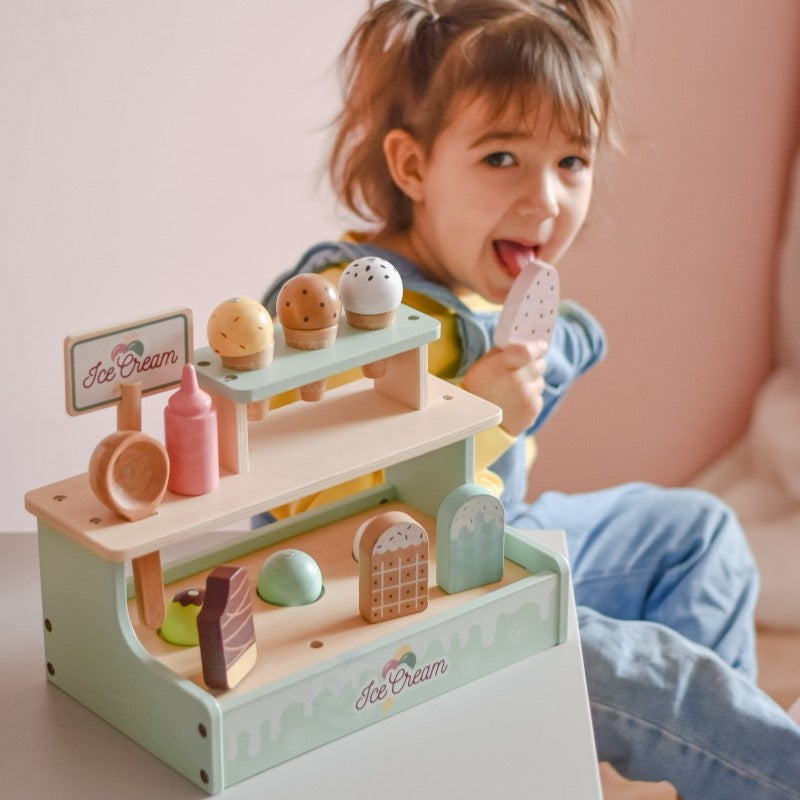 a child's hand serving a towering green wooden ice cream cone with magnetic scoops