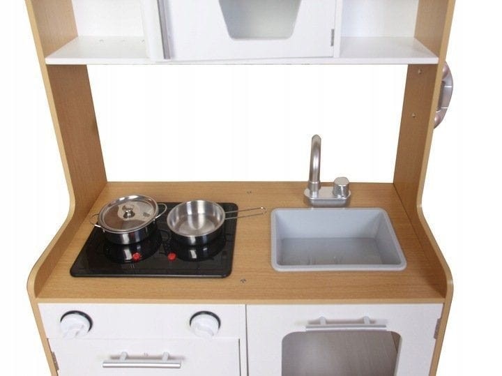 a child's hand turning the dial on the wooden toy kitchen, activating its glowing hob lights