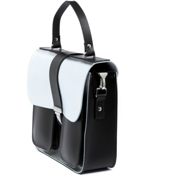 a playful shot of a silver leather bag with a chocolate calf hair base, held at a fun angle against a bright background